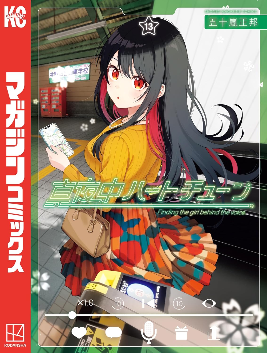 『真夜中ハートチューン』第13巻の表紙イラスト。黒髪に赤いインナーカラーが入った少女が、駅のホームでスマートフォンを持ちながら振り返っている。黄色のニットとカラフルなスカートを合わせた私服姿が特徴的で、画面には動画配信アプリ風のUIが表示されている。背景には駅構内や改札機が描かれ、作品タイトルが中央に配置されたデザイン。